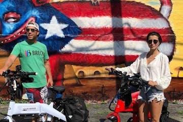 man and woman standing with ebike in front of mural