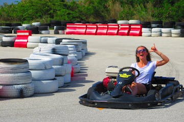 A woman throwing up the shaka sign while driving a go-kart