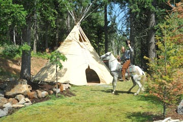 Woman on horse next to TeePee