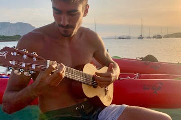 a person holding a guitar in front of a body of water