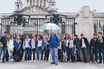 Group photo of a tour group with tour guide Arthur in front of it holding an umbrella