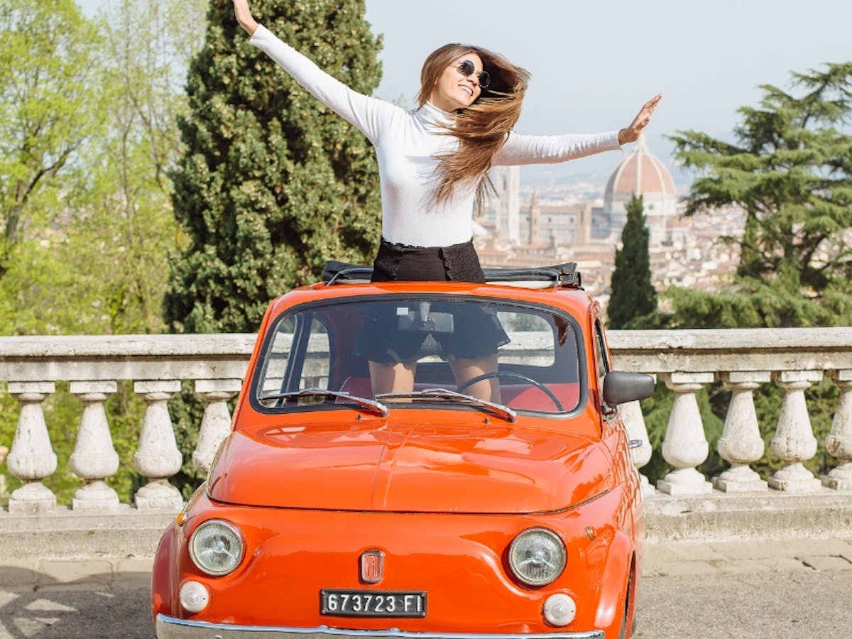 Girl sitting in red Fiat 500 in Tuscany