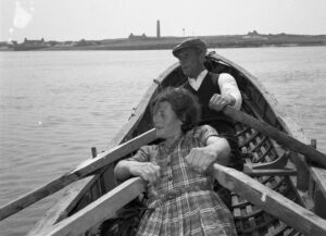A man and woman rowing a boat with Scattery Island in the background