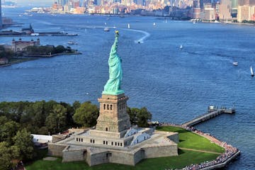 aerial view of statue of liberty on water with new york city in background