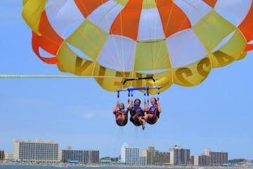 Three ladies parasailing in a bright green and orange parasail