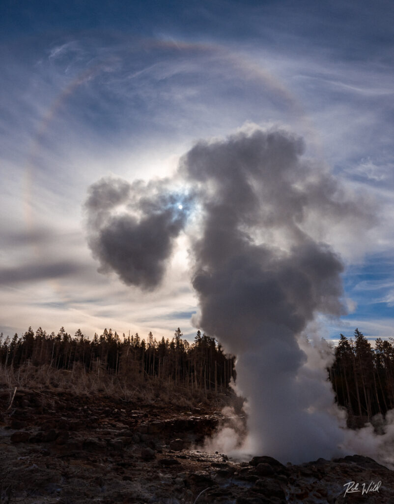 Steamboat Geyser in steam phase, positioned in front of the sun at Norris Geyser Basin in Yellowstone National Park.