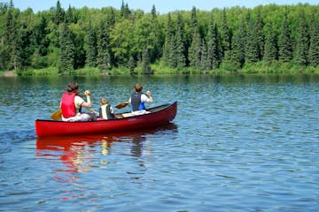 Two people and a child canoeing on a lake