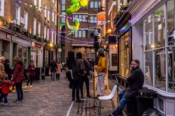 A narrow side street next to Carnaby Street with a garland attached to the walls of each side
