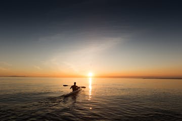 A kayaker paddling toward the sunset