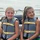 Two girls in life vests on a boat