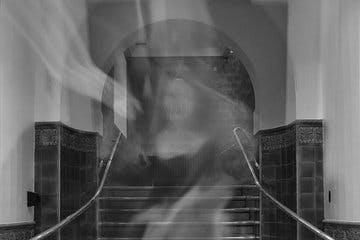 Black and white image of a ghost in front of a staircase