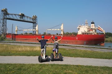 Two people holding hands on Segways