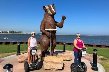 two women on Segways posing in front of a badger statue
