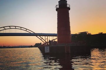 Gold sunset behind a red light house and huge yellow bridge