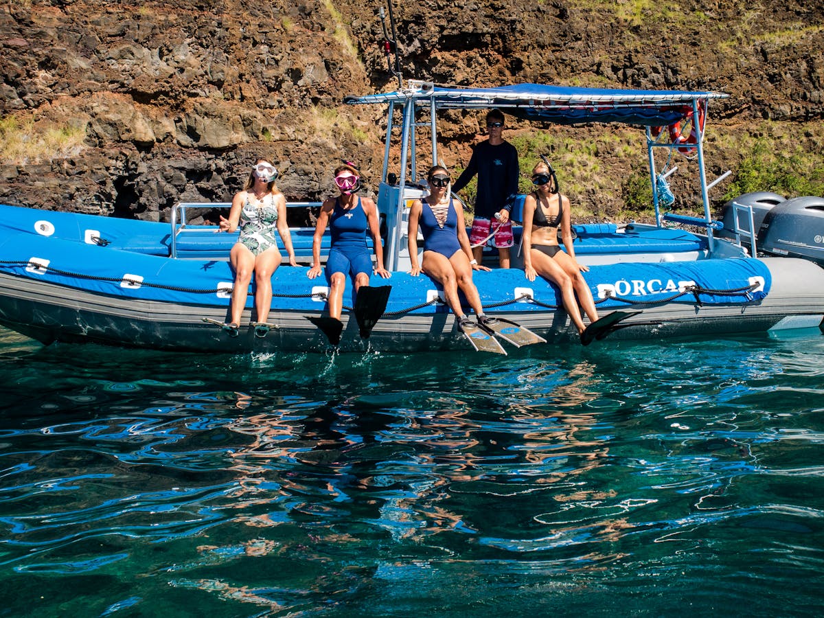 group of snorkelers sitting on side of blue boat