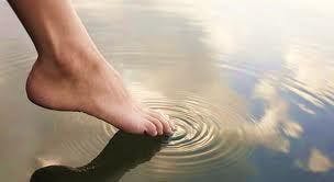 a close up of a womans foot touching the water's surface at the beach
