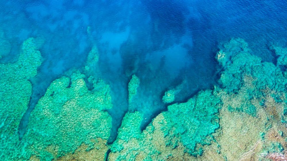 aerial view of coral reefs below tropical water