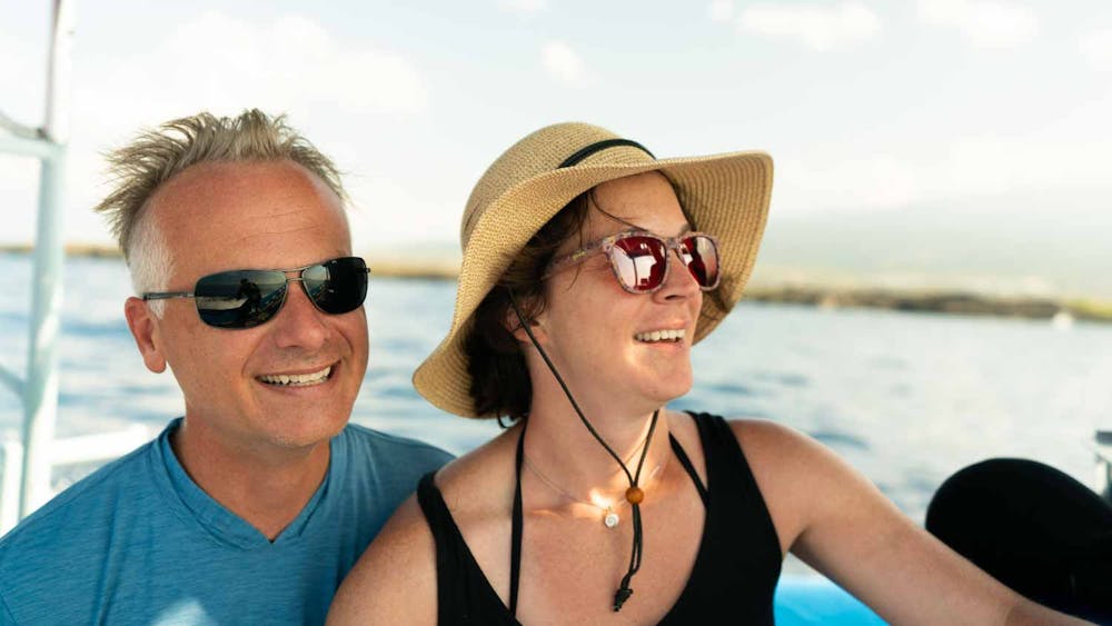 closeup headshot of a couple smiling on a boat with the ocean behind