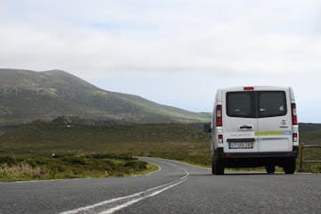 A white van on a road and hills in the background