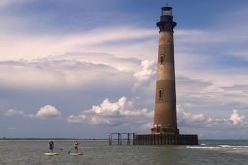lighthouse with two people paddle boarding