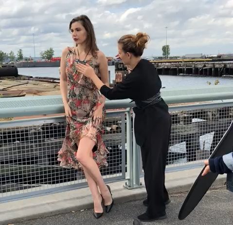 a stylist pinning clothes on a female model during a fashion shoot