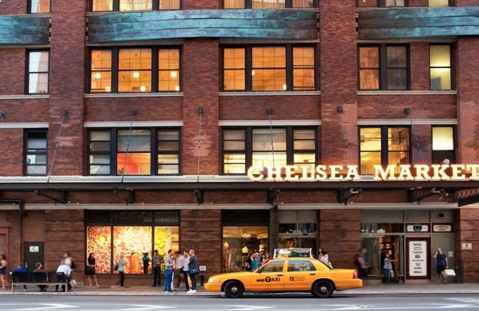 a taxi cab passing in front of a brick building