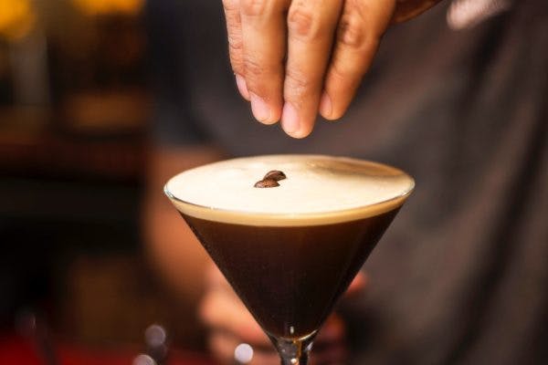 a close up of a person holding putting coffee beans on an espresso martini