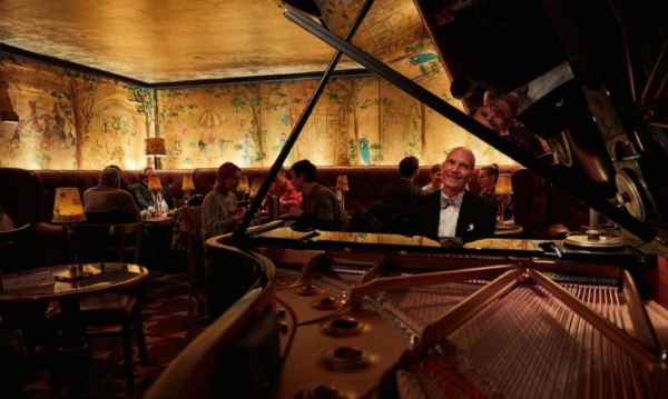 a group of people in a fancy bar with a piano