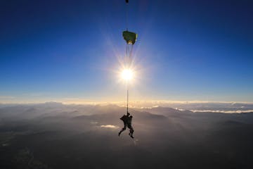 A person skydiving as the sun sets in the background
