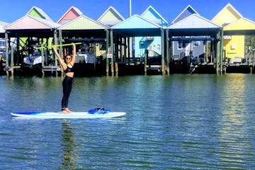 woman stand up paddle boarding on the water in front of colorful houses