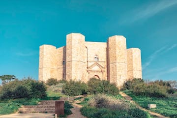a large stone building with Castel del Monte, Apulia in the background