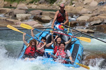 A group of rafters hold their paddles above their heads while white water rafting the lower Animas River
