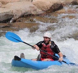 man with white helmet paddles through white water on the lower Animas River