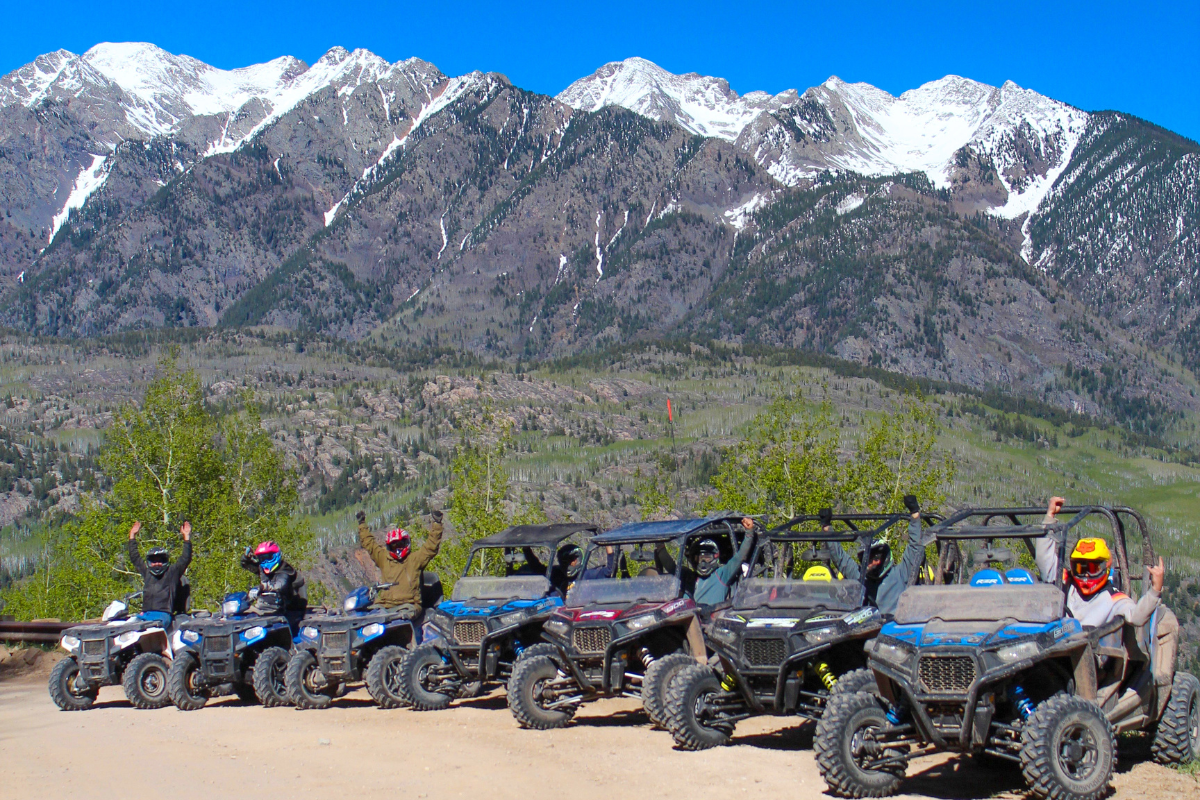 a group of people on UTV's and ATV's in front of the san juan mountains in colorado