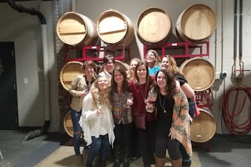 group of friends smiling in front of wine barrels