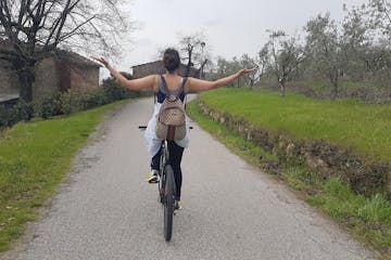 a woman bikes with open arms