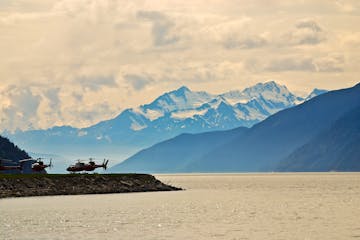 Helicopter landing on landing pad near lake in Alaska