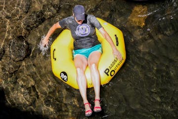 a woman on a yellow river tube floats on a river