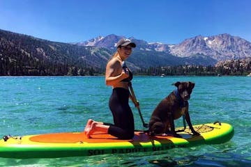 a woman and her dog on a paddleboard