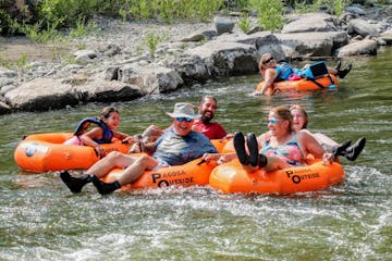 a group of people on tubes laughing while they float a river
