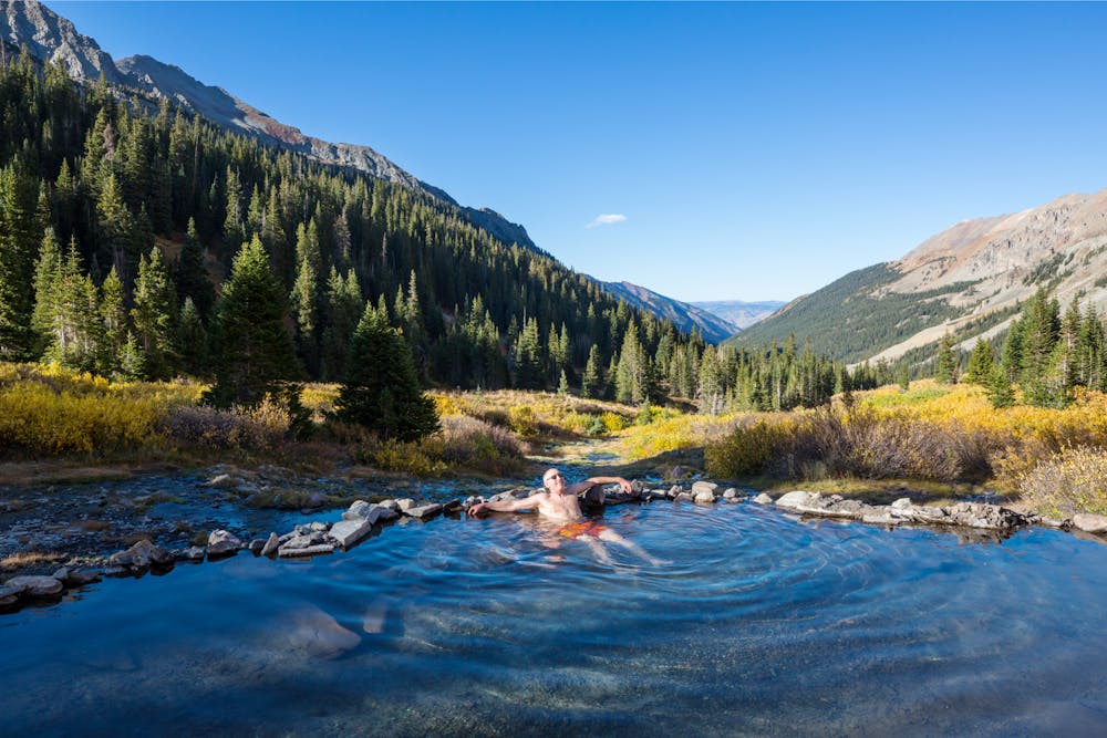 A man sits back in a natural hot spring pool