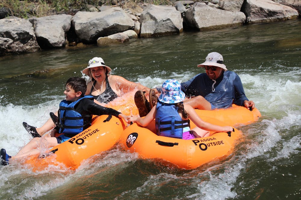 a family of four floats down a colorado river in orange tubes