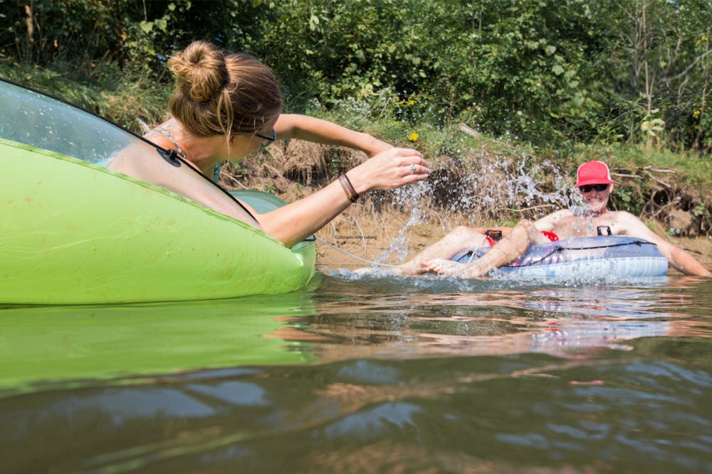 A woman splashes a man while river tubing in colorado