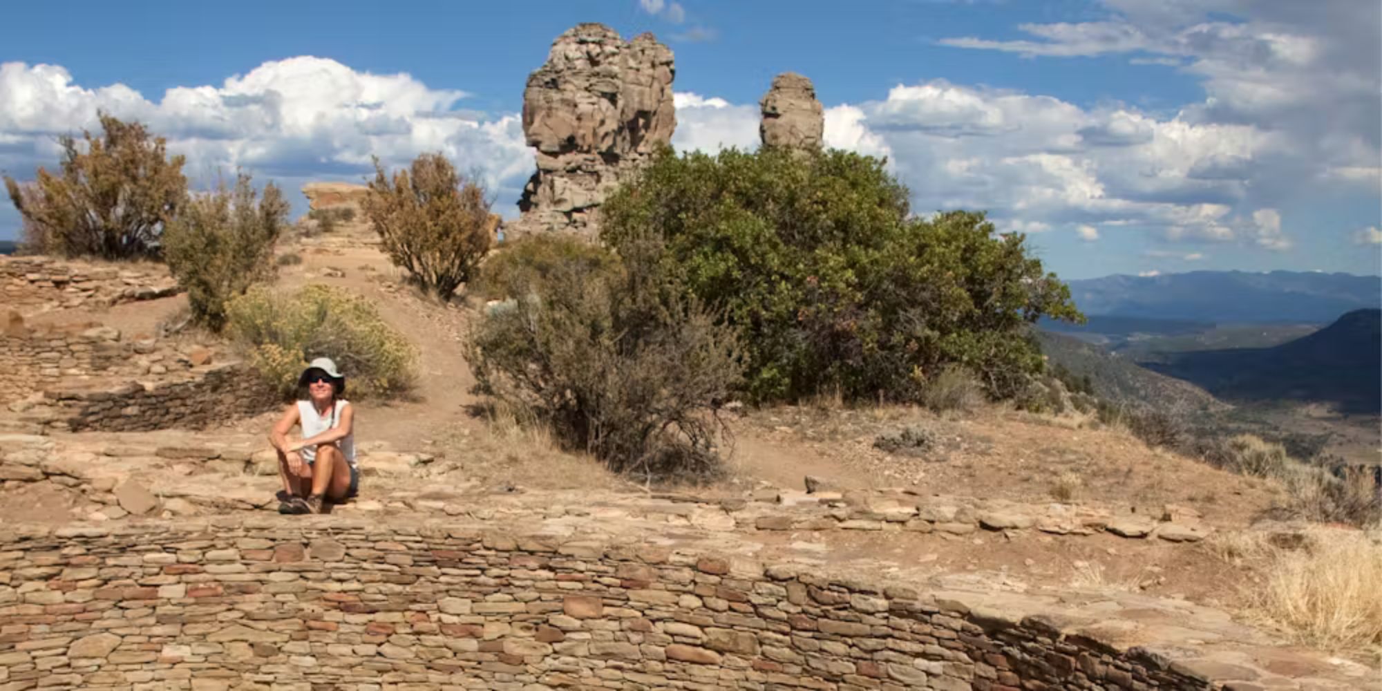 a woman sits and poses in front of chimney rock Colorado