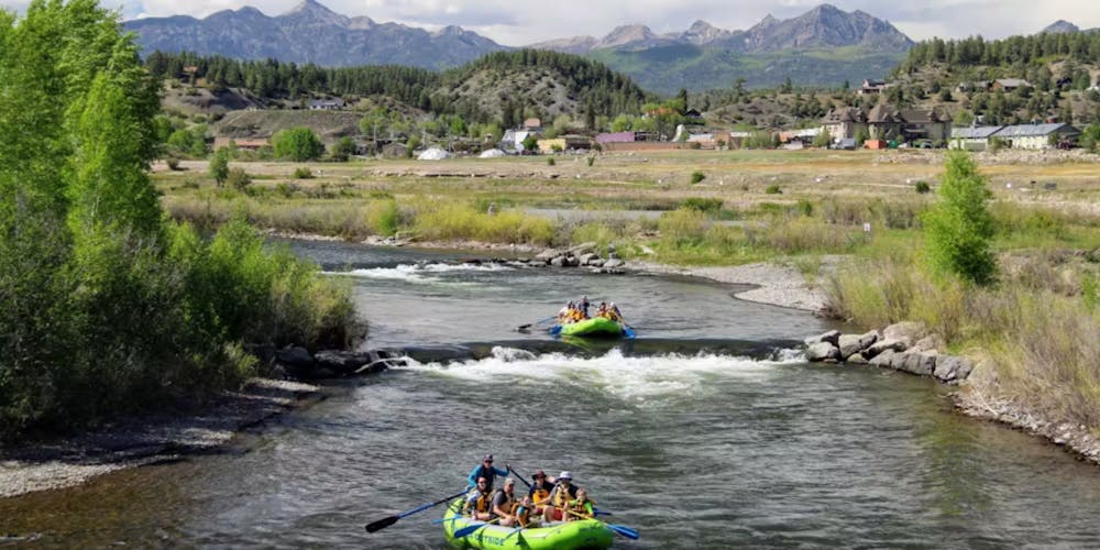 two green boats raft down a river near Chimney rock colorado