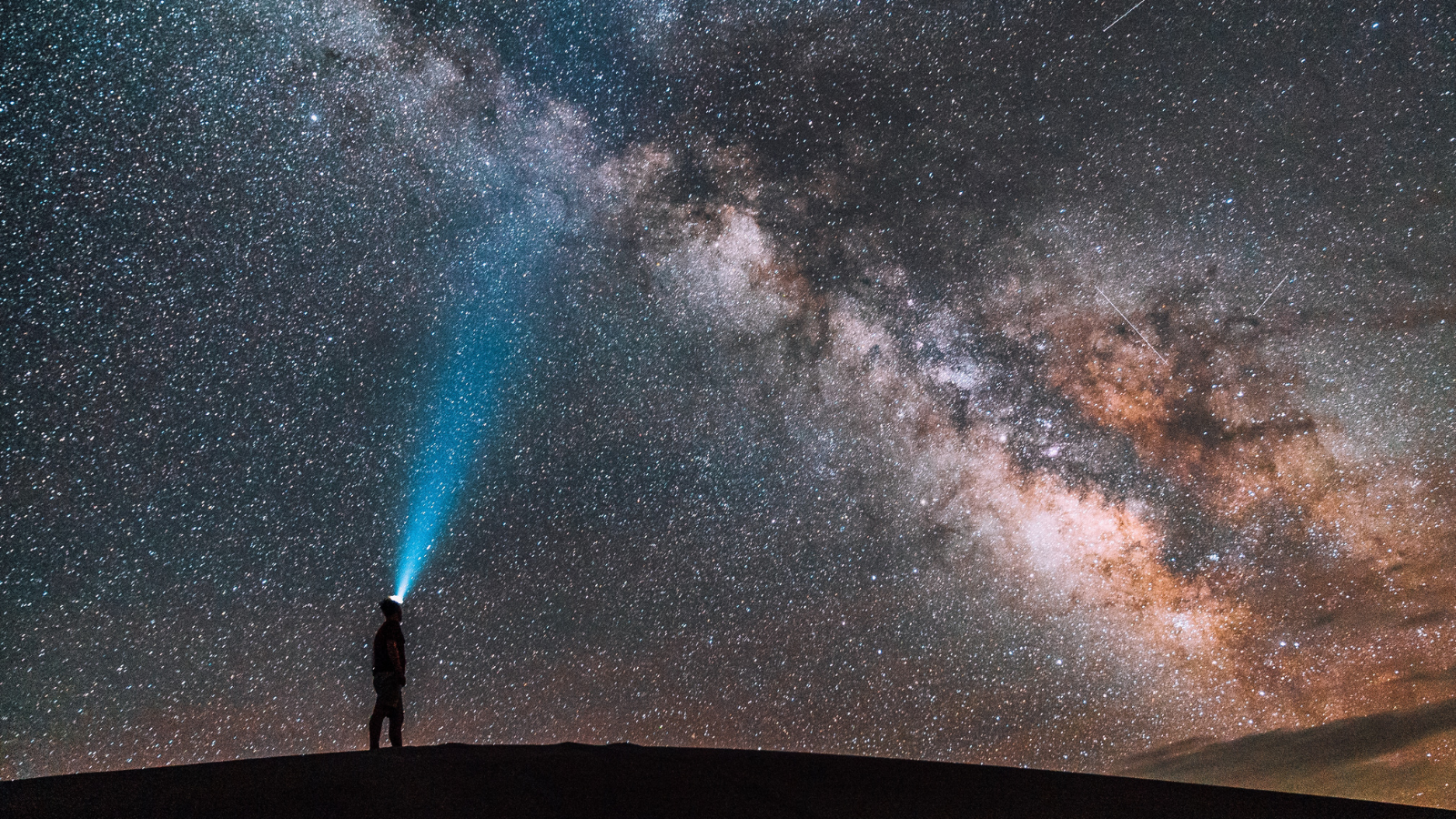 A person with a headlamp looking up at the night sky