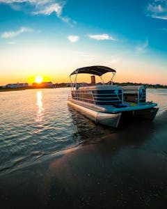 Pontoon boat sitting on a beach at sunset