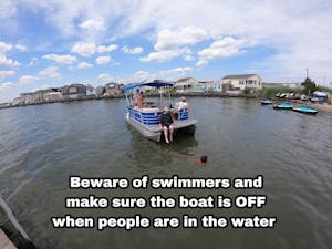 a boat with people on it and a swimmer in the water