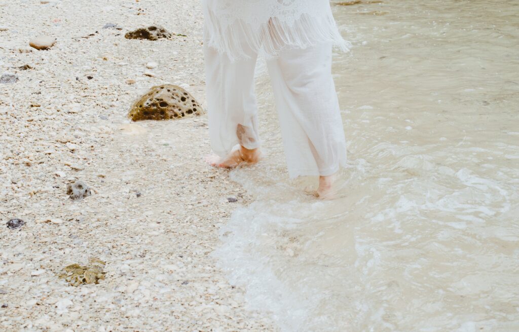 A person in white walking on a seashore