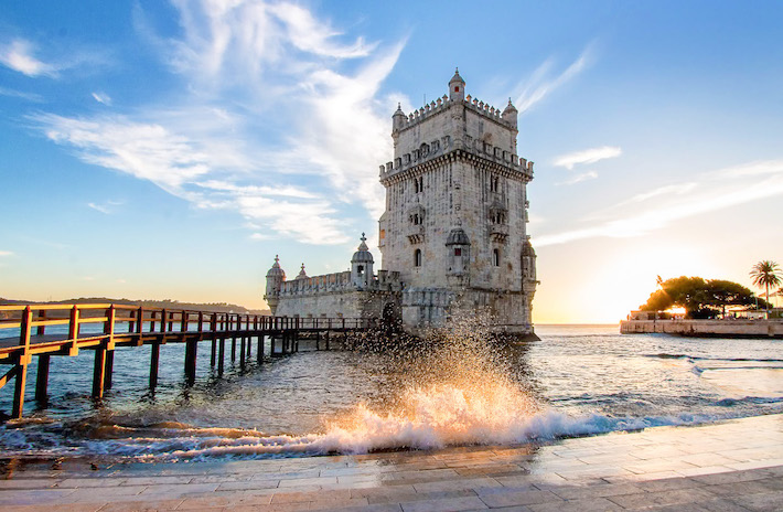 a close up of a pier next to a body of water with Belém Tower in the background